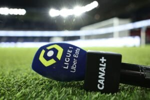 Micro Canal+ avec logo Ligue 1 Uber Eats posé sur la pelouse d’un stade de football éclairé en nocturne